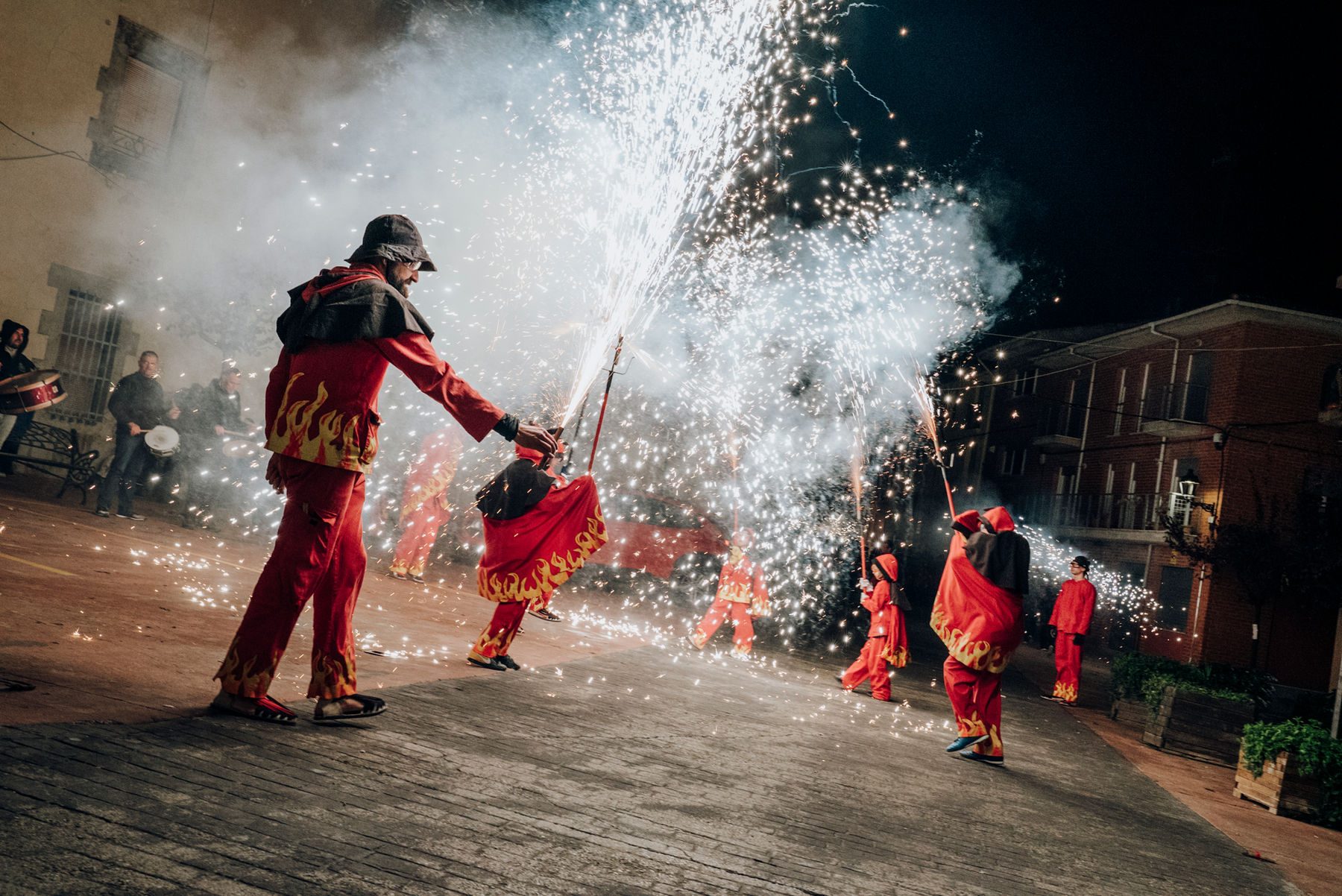 Correfoc amb fum i guspires il·luminant la plaça